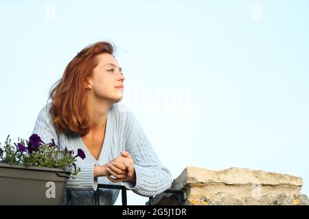Relaxed woman looking away from a balcony at home Stock Photo