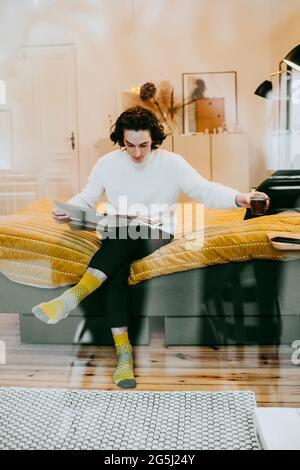 Man reading newspaper while sitting in bedroom at home Stock Photo