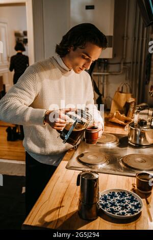 Man pouring coffee in cup at home Stock Photo
