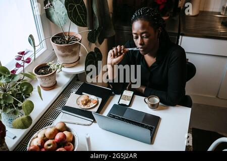 Young female entrepreneur sitting with laptop while working from home Stock Photo