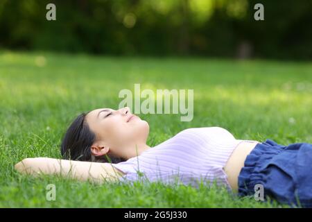 Mixed race woman relaxing lying on the grass in a green park Stock Photo