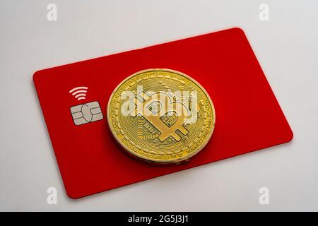bitcoin on red debit card with chip and wireless feature on white background, bitcoin concept, selective focus Stock Photo