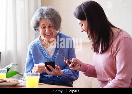 An elderly woman uses a tablet to view content on social networks - Elderly people and modern technologies - A grandmother in a room with a gadget use Stock Photo