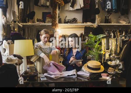 Multi-ethnic female colleagues packing product in box at clothing store Stock Photo