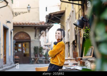 Italy, Tuscany, Pistoia, Smiling woman leaning against table in outdoor cafe Stock Photo