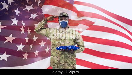 Composition of saluting male soldier wearing face mask, against waving ...