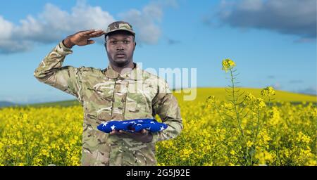 Composition of saluting male soldier holding helmet, against american ...