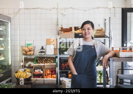 Smiling female owner with hand in pocket standing at store Stock Photo