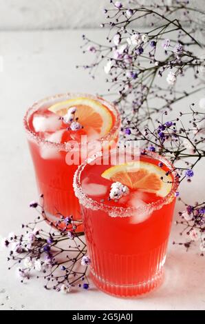 Cold grapefruit cocktail with ice and flowers in a glass glass Stock Photo