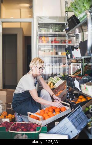 Caucasian female employee arranging fruits in tray at store Stock Photo