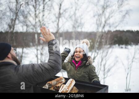 Happy girl giving high five to father during winter Stock Photo