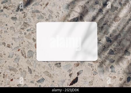 Blank business card, invitation mockup in sunlight. Terrazzo background. Marble stone texture, palm tree leaf shadow overlay. Modern template Stock Photo