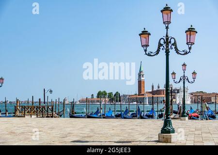A Streetlamp with Gondolas mored in the morning sun in front of St. Mark's Square with San Giorgio di Maggiore church in the background Venice, Italy Stock Photo