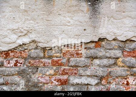 Plastered bricks with pieces of stucco. red, textured wall with a damaged surface. Old, abstract background. Stock Photo