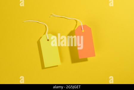 blank rectangular paper yellow and orange price tags with white rope on yellow background, top view Stock Photo