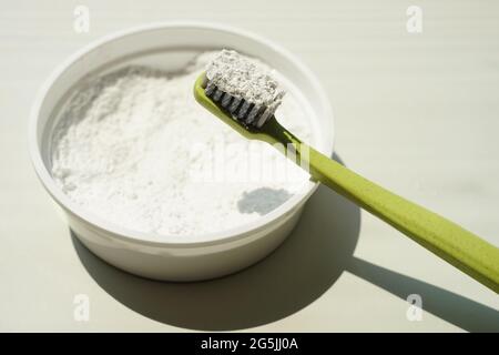 Green plastic toothbrush with tooth-powder on beige table. Stock Photo