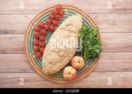 whole meal bread, apple and cherry tomato on table  Stock Photo