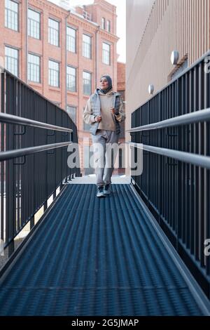 Vertical full length portrait of modern Middle-Eastern woman waking towards camera in city Stock Photo