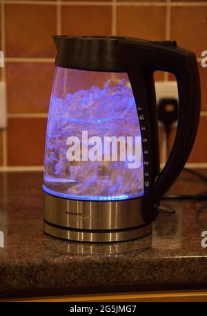 A see-through kettle boiling water, illuminated by a blue light inside Stock Photo