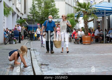 Freiburg im Breisgau, Germany, June 26, 2021: The »Bächle« that runs through the entire old town attracts a child to play on a Saturday. The passers-b Stock Photo