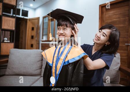 Asian mother and kid preparing on her kinder graduate day at home Stock Photo