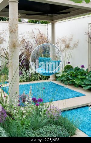 Contemporary small town garden with columns, swing seat and blue carpet Stock Photo