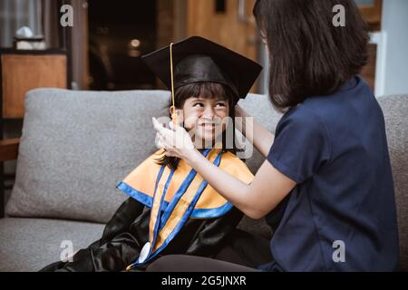 Asian mother and kid preparing on her kinder graduate day at home Stock Photo