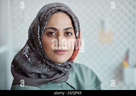 Close up portrait of confident Middle-Eastern woman wearing headscarf in office and looking at camera, copy space Stock Photo
