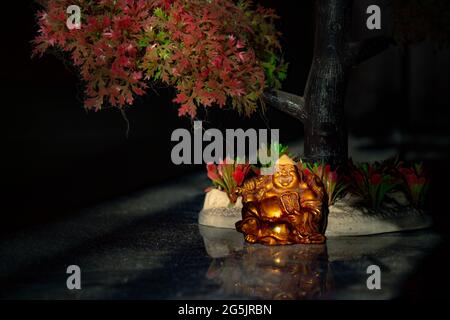 Laughing Buddha Statue on under the Tree. Statue of Laughing Buddha. Statue of Kubera. Stock Photo