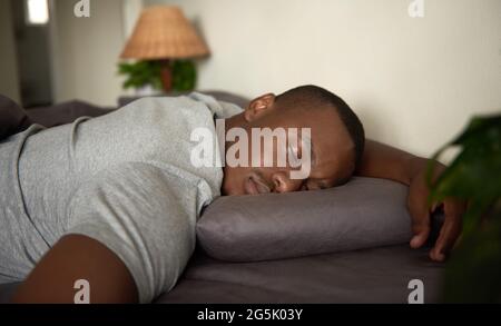 Young African man lying fast asleep in his bed at home Stock Photo