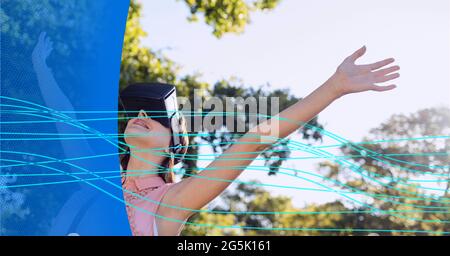 Composition of blue light trails over woman wearing vr headset Stock Photo