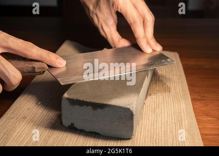 Sharpen a cleaver knife with a stone Stock Photo