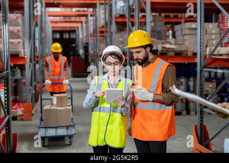 Two workers in hardhats scrolling through data in tablet Stock Photo