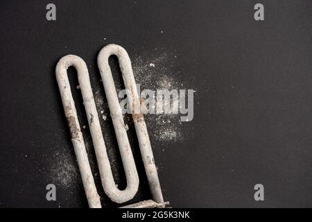 Damaged heating element of washing machine with scum and sediment on black background Stock Photo