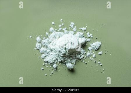 Alginate mask powder or green cosmetic clay bentonite powder, dry body wrap sample texture on green background. Skin care, body care concept. Stock Photo