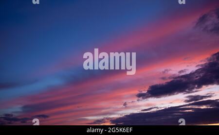Multi-colored clouds on the dramatic sky. Consumption and sunset clouds. Natural landscape. Pink and blue feather cloud. Stock Photo