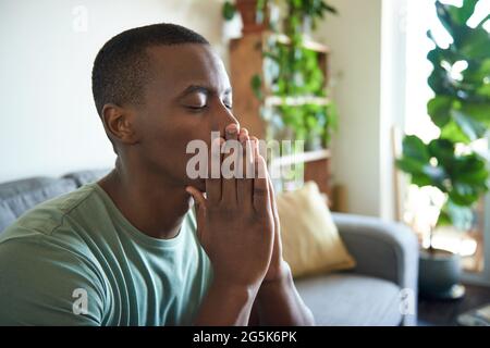 Depressed young African man sitting with his eyes closed Stock Photo