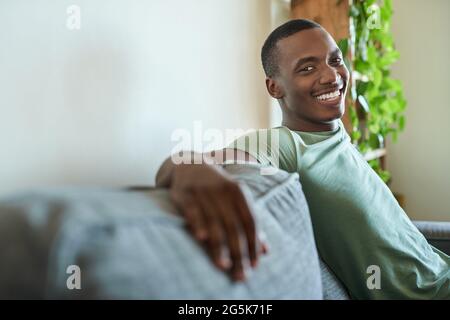 Smiling young African man relaxing on his sofa at home Stock Photo