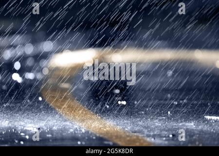 Heavy rain or downpour, raindrops fall on the asphalt, night or evening. Stock Photo