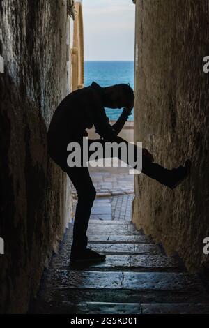 Silhouette man stands on dark tunnel with sea background Stock Photo