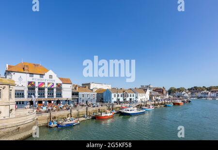 Tourists, boats moored quayside in Weymouth, a seaside town and popular holiday resort on the estuary of the River Wey, Dorset, south coast England Stock Photo