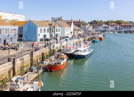 Tourists, boats moored quayside in Weymouth, a seaside town and popular holiday resort on the estuary of the River Wey, Dorset, south coast England Stock Photo