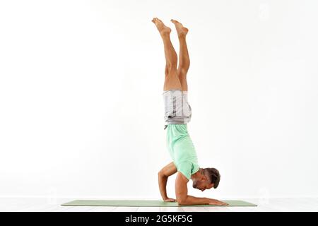 Young man acrobatics gymnastic doing a handstand studio isolated on white background, athletic sportsman Stock Photo