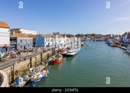 Tourists, boats moored quayside in Weymouth, a seaside town and popular holiday resort on the estuary of the River Wey, Dorset, south coast England Stock Photo