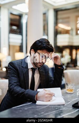 Vertical portrait of successful Middle-Eastern businessman working in hotel lobby during business trip Stock Photo