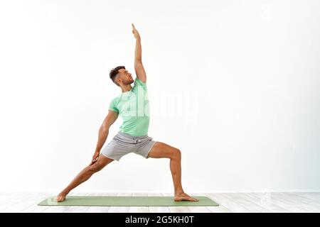 Attractive Young Man practicing advanced yoga on white