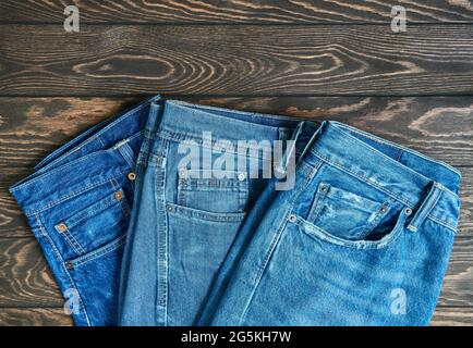 Blue jeans in a row, stack of denim pants, composition on wooden background with copy space Stock Photo