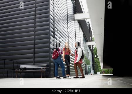 Three students hanging out around their campus Stock Photo