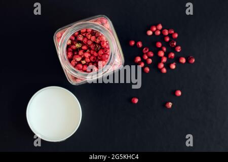 Pink peppercorns in a glass jar on a dark background, shallow depth of sharpness, view above Stock Photo