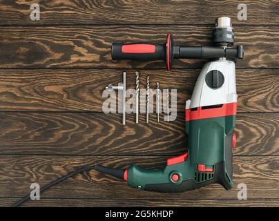 Professional electric drill and shatterproof drill  bits on wooden background, construction industry Stock Photo